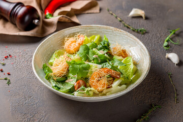 salad with shrimp, avocado and greenery on plate on brown table