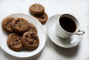 Tea pair and oatmeal cookies with chocolate on a white background. Delicious lunch with tea and sweet cookies. Porcelain tea set with a hot drink.