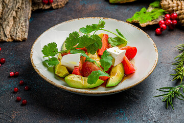 vegetable salad with avocado, cheese and tomatoes on plate