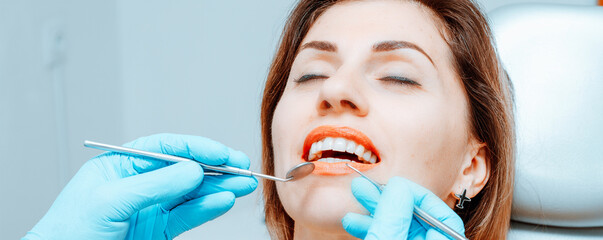 Dentist and patient during treatment in dentistry, young woman undergoing dental checkup in modern...