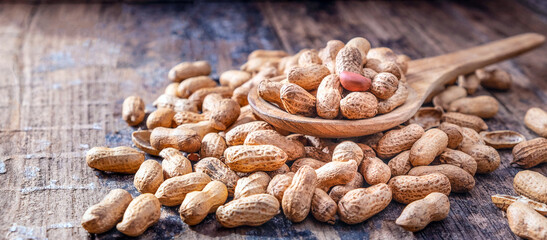 Dried peanuts or nuts on wooden background.Peanut shells on a wooden spoon