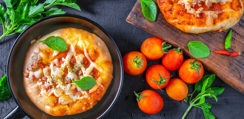 Top view of home made pizza, vegetables, ingredients on a Black wooden  background. Pizza is cooking in the pan. Pizza