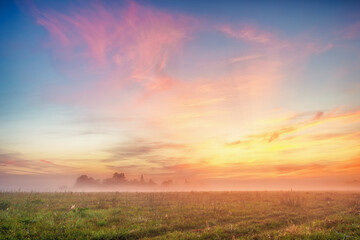 Bright yellow-pink sky before dawn in a foggy field. A natural landscape. 