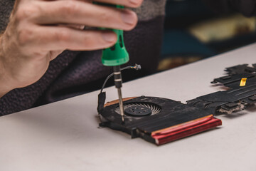 fixing the fan in the laptop cooling system with screws and screwdriver. laptop maintenance. updating computer components. the concept of computer equipment, repair, technology and modernization.