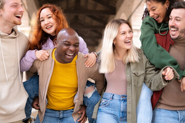 Multiracial young people walking happily on the street - Guys and girls having fun together -...