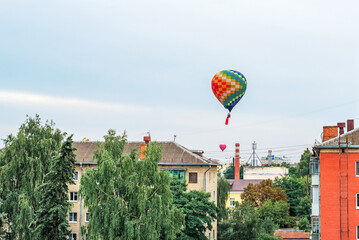 Colorful balloons fly in the sky above the roofs of high-rise buildings in a provincial city