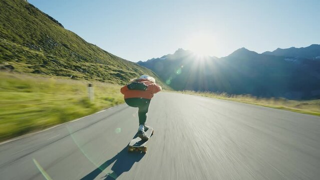 Cinematic downhill longboard session. Young woman skateboarding and making tricks between the curves on a mountain pass. Concept about extreme sports and people