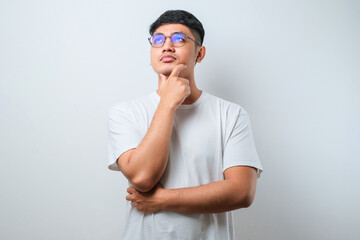 Young asian man thinking worried about a question, concerned and nervous with hand on chin