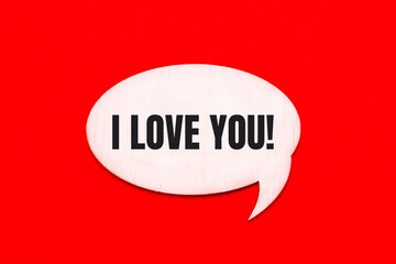 On a bright red background, a light wooden curly card with the text I LOVE YOU