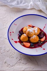 Profiteroles with strawberries, powdered sugar, blackberries, blueberries, jam and mung bean salad