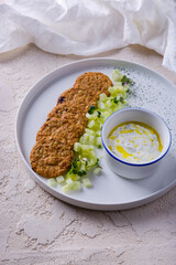 Oatmeal cookies with pieces of cucumber sauce in a bowl and mung bean salad