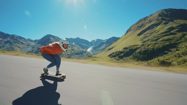 Cinematic downhill longboard session. Young woman skateboarding and making tricks between the curves on a mountain pass. Concept about extreme sports and people