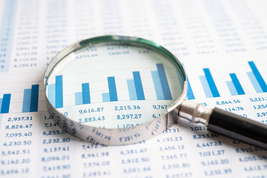 Magnifying glass on chart graph spreadsheet paper. Financial development, Banking Account, Statistics, economy, Stock exchange trading, Business office company meeting concept.