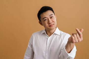 Mid asian man wearing shirt smiling while rubbing his fingers