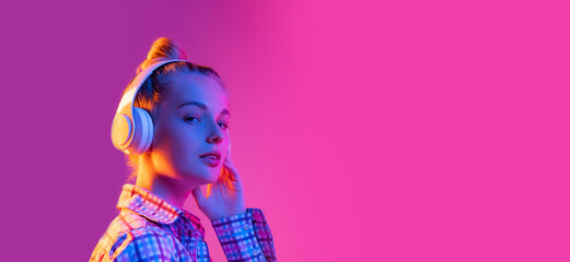 Portrait of adorable young girl, student wearing plaid shirt isolated on magenta color background...