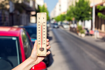 Hot weather. Thermometer in front of an urban scene during heatwave.