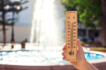 Hot weather. Thermometer in front of fountain during heatwave.