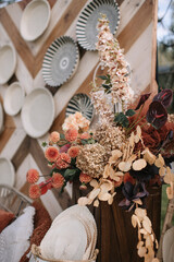 A careless bouquet in a natural style with dry hydrangeas in a wooden tub. In the background is a wooden wall decorated with black and white plates.