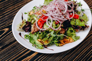 There is a dish for vegetarians on the white plate on the wooden table.
