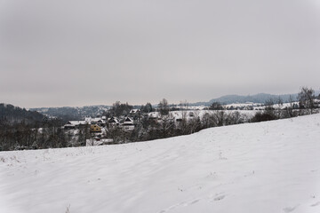 Fototapeta na wymiar Snowy panoramic landscape in the mountains, little village, hills covered with snow, winter weather