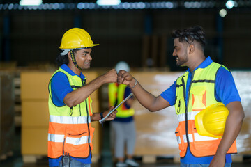 Happy Asian warehouse workers having fun and fist bumping during beginning start work in morning.