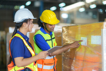 Asian couple warehouse workers checking shipment status on digital tablet computer prepare for delivery to customer. Employees teamwork.