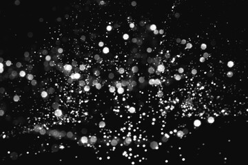 White gray blurred abstract bokeh lights on black background. Snowy shiny glitter sparkle stars for celebrate