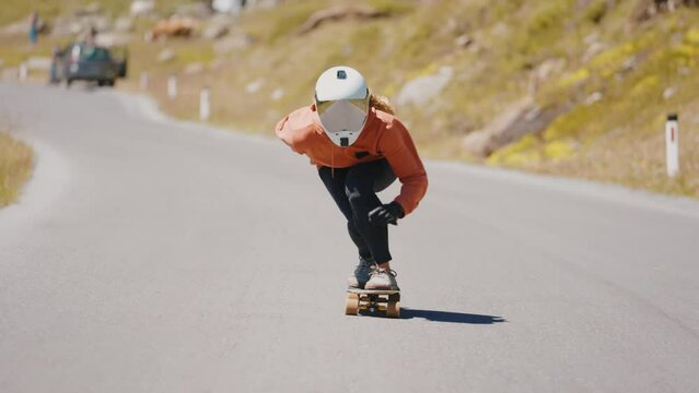 Cinematic downhill longboard session. Young woman skateboarding and making tricks between the curves on a mountain pass. Concept about extreme sports and people