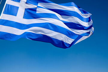 View of the greek flag waving in the air and a blue sky in the background