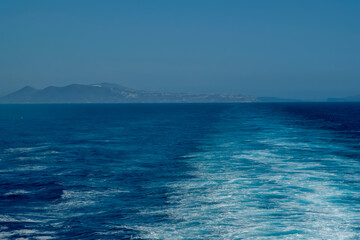 Panoramic view of Santorini island and wave trails of a floating ferry boat