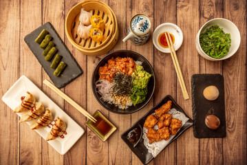 Asian food dishes set with green tea sweets, gyozas, mochis and poke bowl with soy sauce and wakame