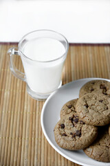 A glass glass with milk on a wooden mat with oatmeal cookies. Afternoon lunch with cookies. Sweet cookies with milk.