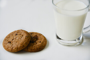 Glass glass with milk on a white background with oatmeal cookies. Afternoon lunch with cookies. Sweet cookies with milk.