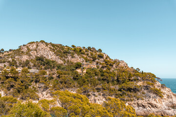 Fototapeta na wymiar Coastal landscape with rocky hills and trees. Shore on Costa Brava in Spain