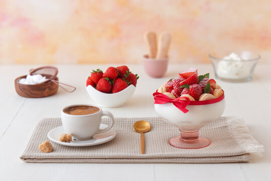 Charlotte, French dessert with strawberries, cup of coffee and ingredients on white wooden table. Selective focus, low angle view, no people.