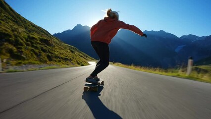 Cinematic downhill longboard session. Young woman skateboarding and making tricks between the curves on a mountain pass. Concept about extreme sports and people