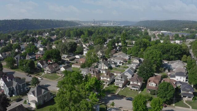 A slow forward summer aerial establishing shot of a small Pennsylvanian town. The Beaver County Shell cracker factory on the Ohio River in the distance.	
