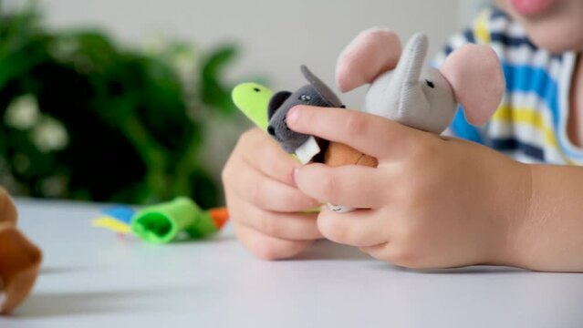 Preschool child plays finger theater, puts toys on his fingers.