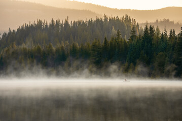 Lone kayak on calm, smoky water at Trillium Lake near Mt. Hood.