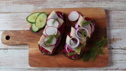 Danish open sandwich Smorrebrod on dark rye bread with herring, salmon, beetroot, red onions, and radish