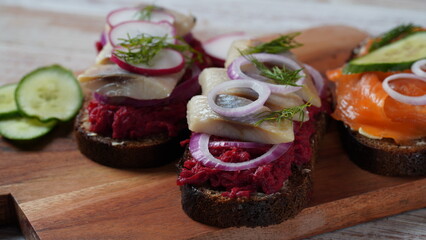 Danish open sandwich Smorrebrod on dark rye bread with herring, salmon, beetroot, red onions, and radish