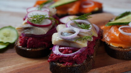 Danish open sandwich Smorrebrod on dark rye bread with herring, salmon, beetroot, red onions, and radish