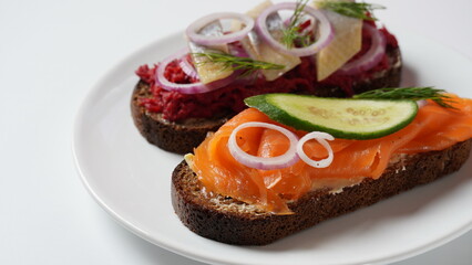 Danish open sandwich Smorrebrod on dark rye bread with herring, salmon, beetroot, red onions, and radish