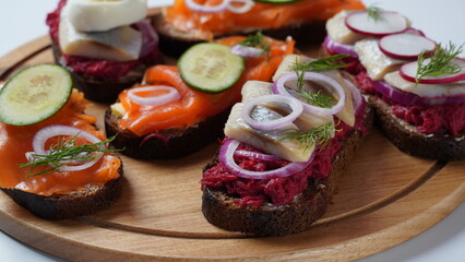 Danish open sandwich Smorrebrod on dark rye bread with herring, salmon, beetroot, red onions, and radish