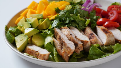 Salad with chicken breast, fresh mango, avocado, cucumber, cherry tomatoes, lettuce. Healthy food concept