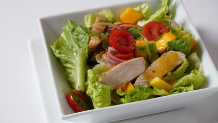 Salad with chicken breast, fresh mango, avocado, cucumber, cherry tomatoes, lettuce. Healthy food concept