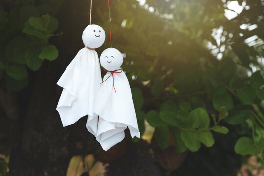 Couple Chasing rain Japanese doll or Teru Teru Bozu hanging on branches tree in the garden and background with copy space.