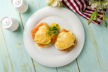 eggs Benedict with salmon on a white plate top view