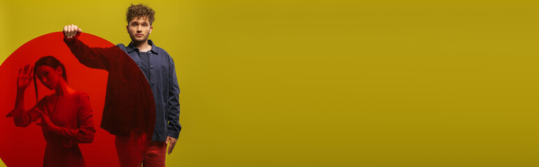 curly man in blue shirt holding round shape glass near woman isolated on green, banner.