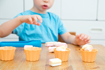 Obraz na płótnie Canvas Fun at home. DIY game for children. Idea for mommy. Marshmallows and cupcake molds. Put as many sweets as the number by the cup. Learning trough the game.